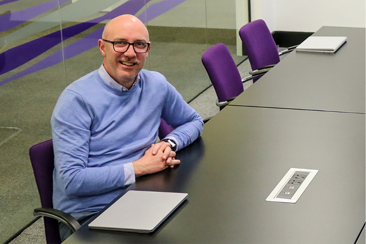 Dyfed Alsop (Chief Executive of the Welsh Revenue Authority) sat in a meeting room smiling.