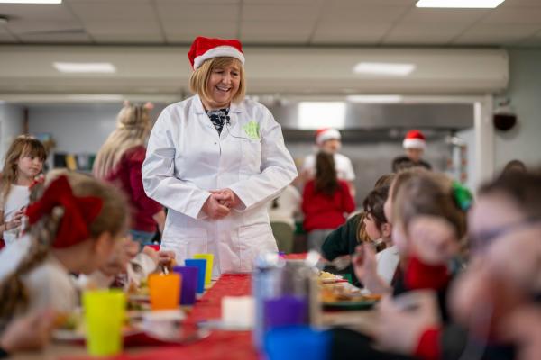 Cabinet Secretary for Education, Lynne Neagle talking to children at school eating their Christmas dinner.